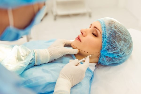 Surgeon is performing a plastic surgery using a scalpel, in a modern operating room, close up